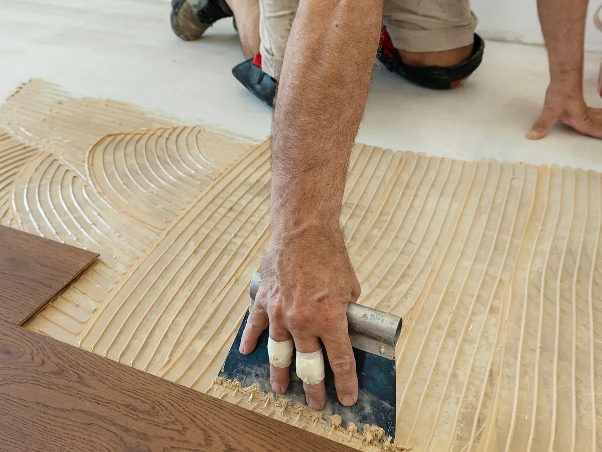 Notched trowel spreading adhesive for an engineered hardwood glue-down over a concrete slab in Sioux Falls, SD