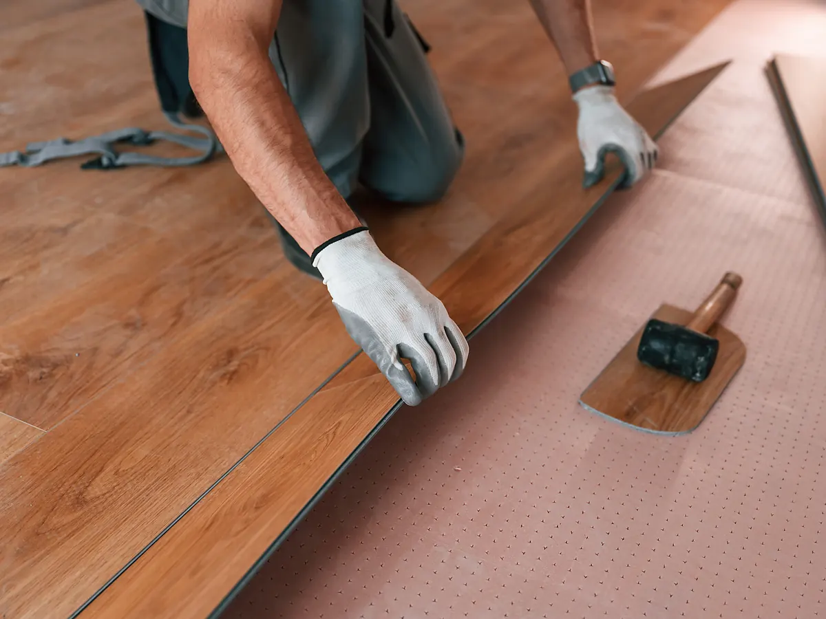Engineered hardwood plank set over underlayment with a tapping block