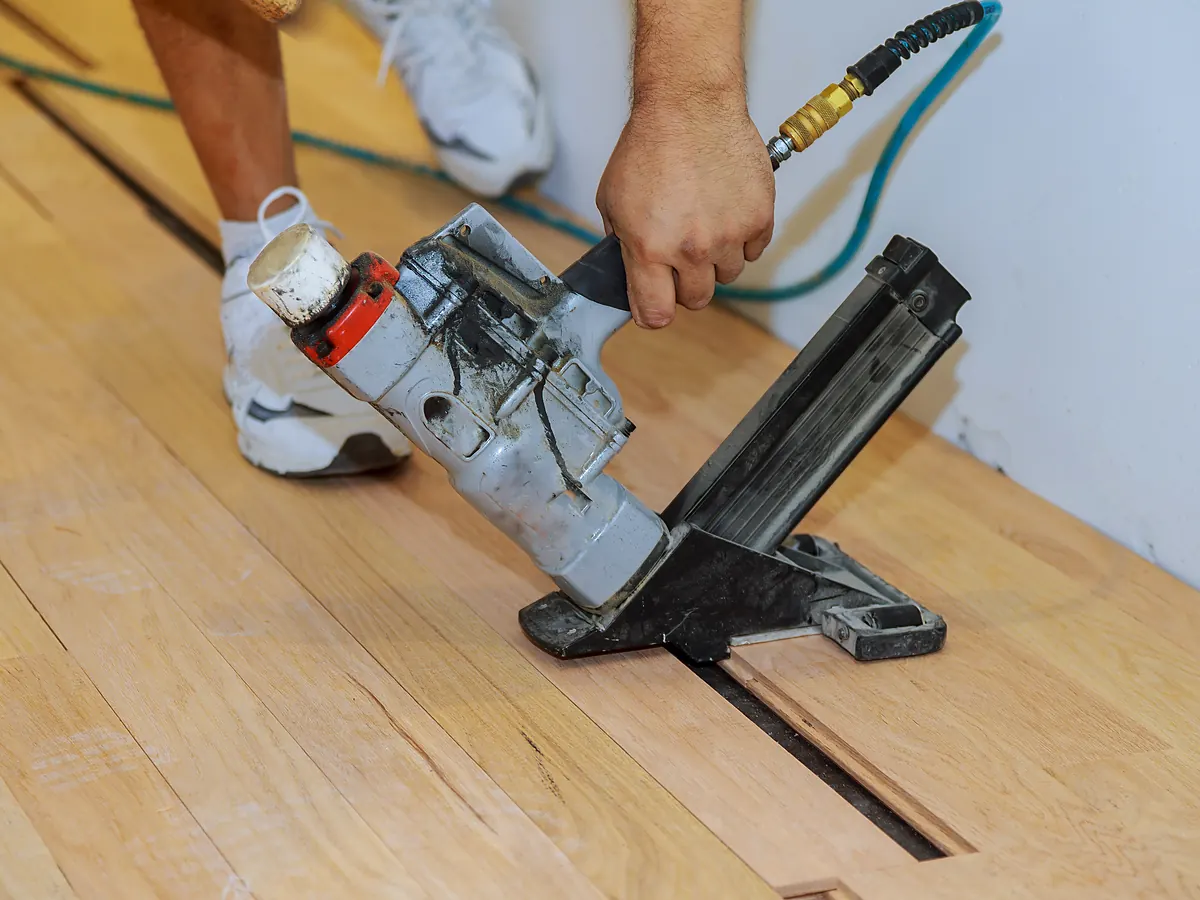 Pneumatic flooring nailer fastening solid hardwood boards to a wood subfloor in Sioux Falls, SD
